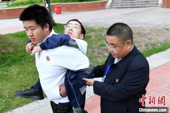 朱金祥背著鐘華強(qiáng)去教室上課的路上，也經(jīng)常碰到值班的校領(lǐng)導(dǎo)和老師前來(lái)搭把手。 卓忠偉 攝