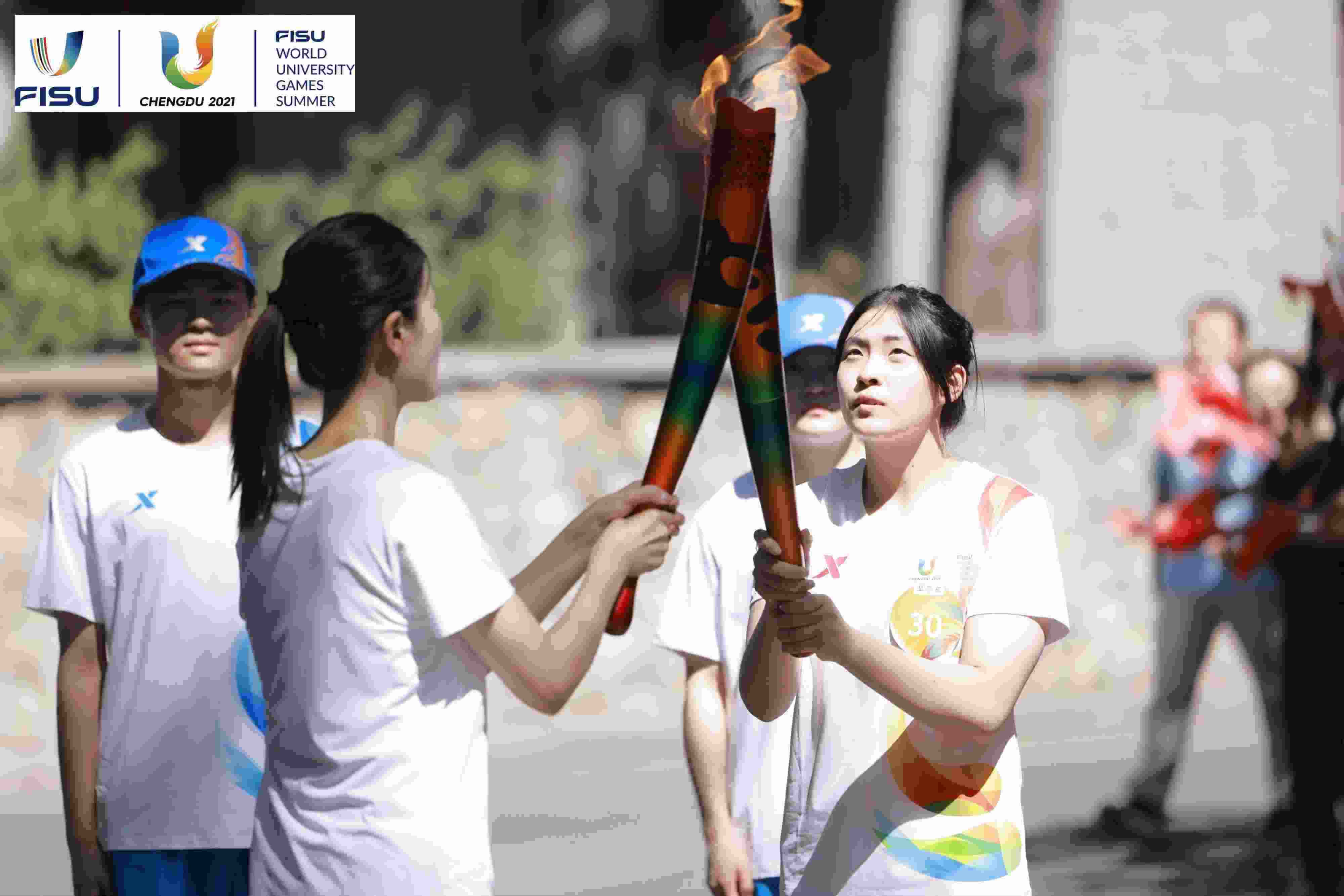 兩名大運(yùn)會火炬手進(jìn)行火炬?zhèn)鬟f。 圖片來源：成都大運(yùn)會執(zhí)委會供圖