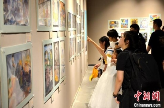 圖為家長(zhǎng)帶著孩子參觀展覽。呂明 攝