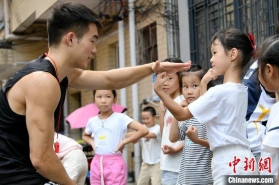 圖為大學(xué)生志愿者在組織孩子們參加體育健身活動。廖光福 攝