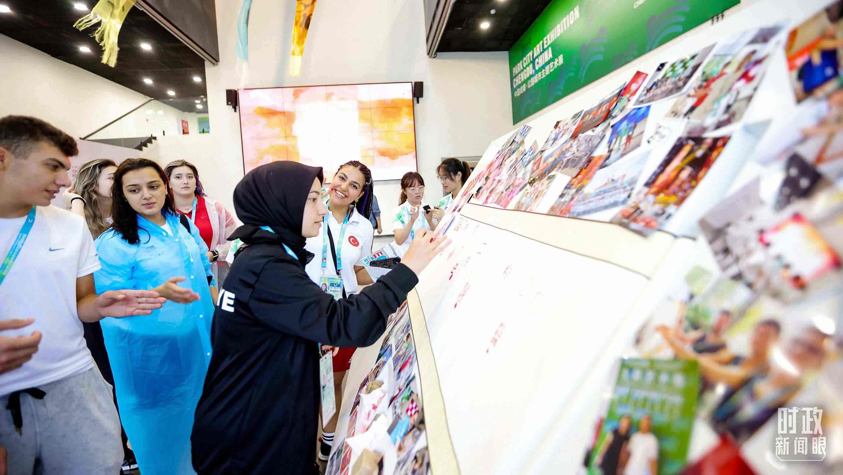 各國(guó)青年運(yùn)動(dòng)員正在參觀成都大運(yùn)村內(nèi)的“雪山下的公園城市，煙火里的幸福成都”主題藝術(shù)展。（總臺(tái)央視記者魏幫軍拍攝）