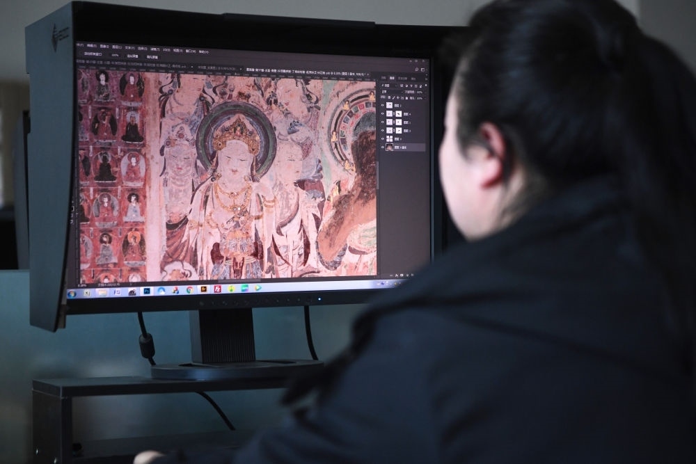 敦煌研究院文物數(shù)字化保護(hù)團(tuán)隊(duì)圖像處理人員年海麗在拼接壁畫圖像（2023年4月25日攝）。數(shù)字化探索為莫高窟的保護(hù)與傳承開辟了全新路徑，數(shù)字技術(shù)讓敦煌文物走出洞窟，跨出國(guó)門，走向“永久保存、永續(xù)利用”。新華社記者 陳斌 攝