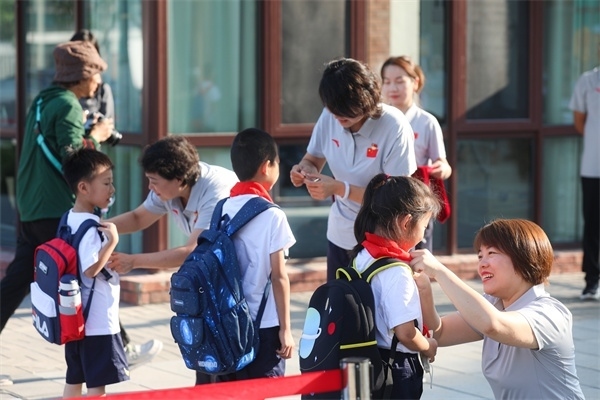8月30日，雄安史家胡同小學(xué)學(xué)生體驗(yàn)學(xué)校生活。老師為學(xué)生佩戴?；?。
