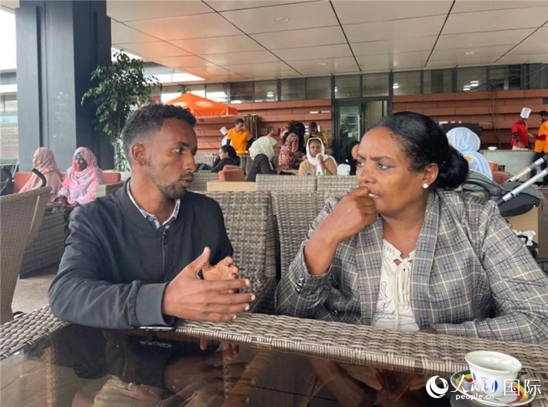 約漢斯（圖左）與德貝拉在友誼廣場咖啡廳交談。人民網(wǎng)記者 趙艷紅攝