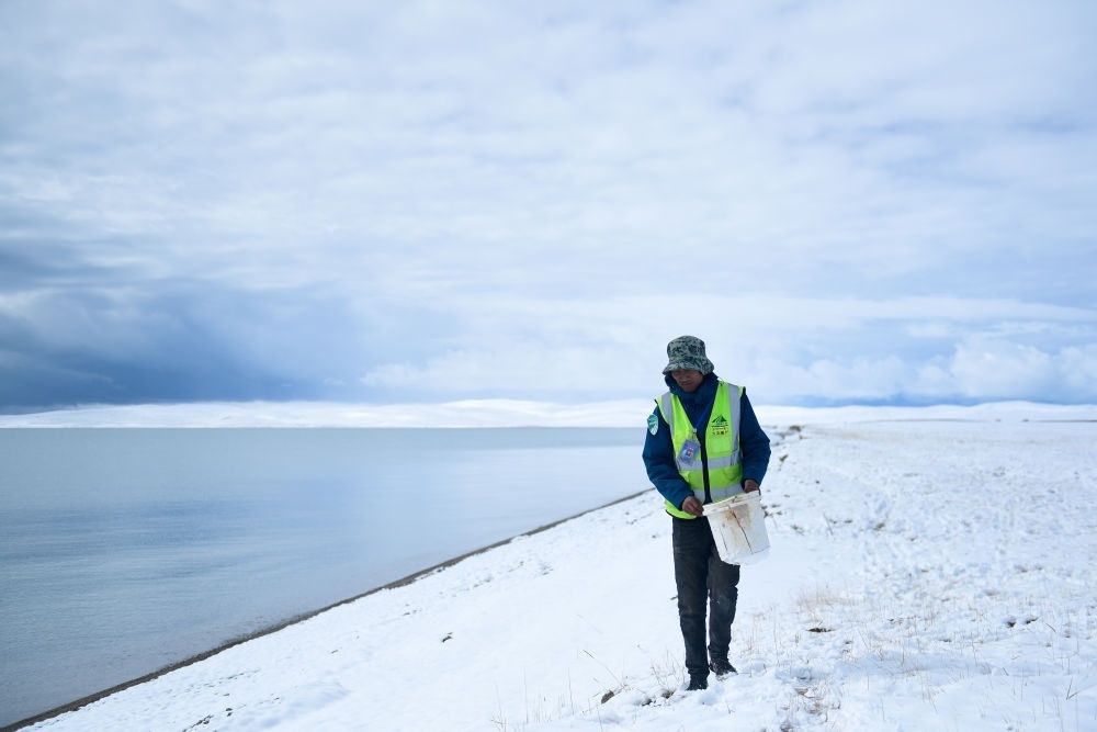 2021年10月20日，在青海省果洛藏族自治州瑪多縣扎陵湖鄉(xiāng)勒那村，三江源國家公園黃河源園區(qū)生態(tài)管護員在扎陵湖邊撿拾垃圾。新華社記者 張龍 攝