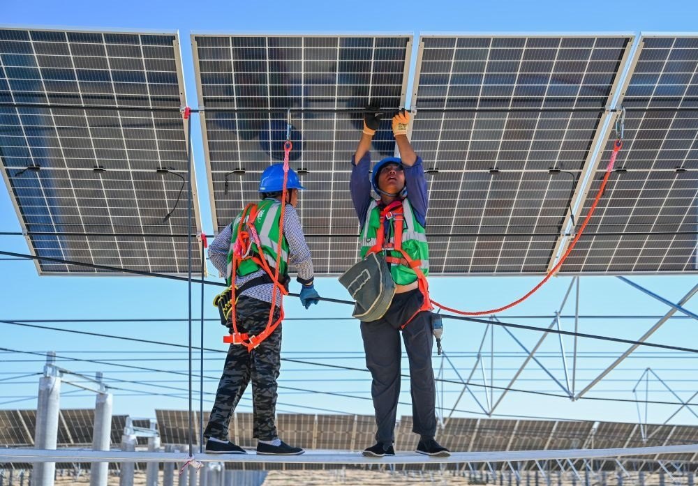 2023年7月22日，工人在位于內(nèi)蒙古杭錦旗庫布其沙漠億利生態(tài)示范區(qū)的蒙西基地庫布其200萬千瓦光伏治沙項目工地安裝光伏板。新華社記者 劉磊 攝