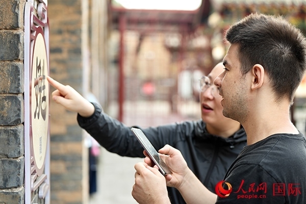 選手安德烈（俄羅斯）在老師指導(dǎo)下學(xué)習(xí)墻壁上張貼的生僻字。人民網(wǎng) 盧鵬宇攝