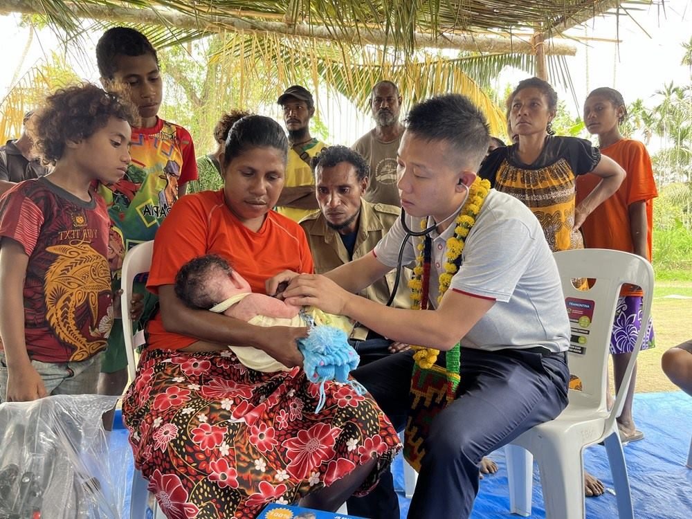 2023年8月5日，在巴布亞新幾內(nèi)亞中央省的一個(gè)村莊里，第12批援巴新中國(guó)醫(yī)療隊(duì)副隊(duì)長(zhǎng)、新生兒科副主任醫(yī)師劉振球?yàn)楫?dāng)?shù)貗雰郝?tīng)診檢查。新華社發(fā)（第12批援巴新中國(guó)醫(yī)療隊(duì)供圖）
