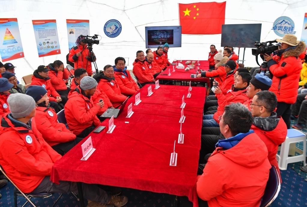 海拔4950米的卓奧友峰科考大本營，科考隊員趙華標(biāo)（手拿麥克風(fēng)看電腦者）在宣讀剛剛接收到的頂峰氣象觀測數(shù)據(jù)，這標(biāo)志著峰頂自動氣象站架設(shè)成功，成功傳回觀測數(shù)據(jù)（10月1日攝）。新華社記者晉美多吉 攝