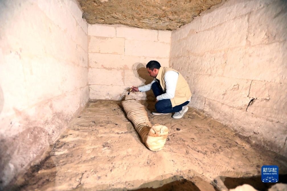 10月15日，在埃及明亞省考古現(xiàn)場，考古人員清理一座石鑿墓中的木乃伊。新華社發(fā)（艾哈邁德·戈馬攝）