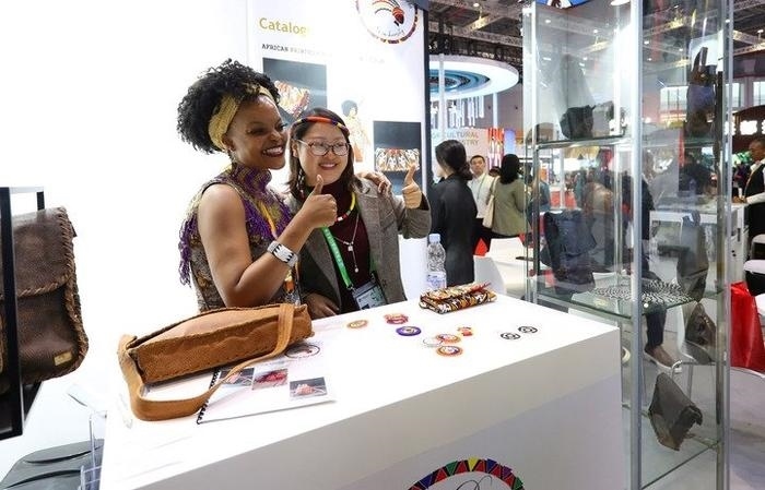 11月6日，一位參觀者（右）在第六屆進(jìn)博會(huì)國(guó)家展南非展臺(tái)試戴傳統(tǒng)首飾。