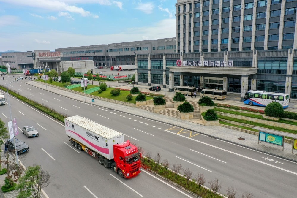 2023年10月11日，滿載筆記本電腦配件、發(fā)電機組件等產(chǎn)品的西部陸海新通道跨境公路班車從重慶南彭公路保稅物流中心駛出，將途經(jīng)廣西憑祥，直達越南（無人機照片）。新華社記者 黃偉 攝