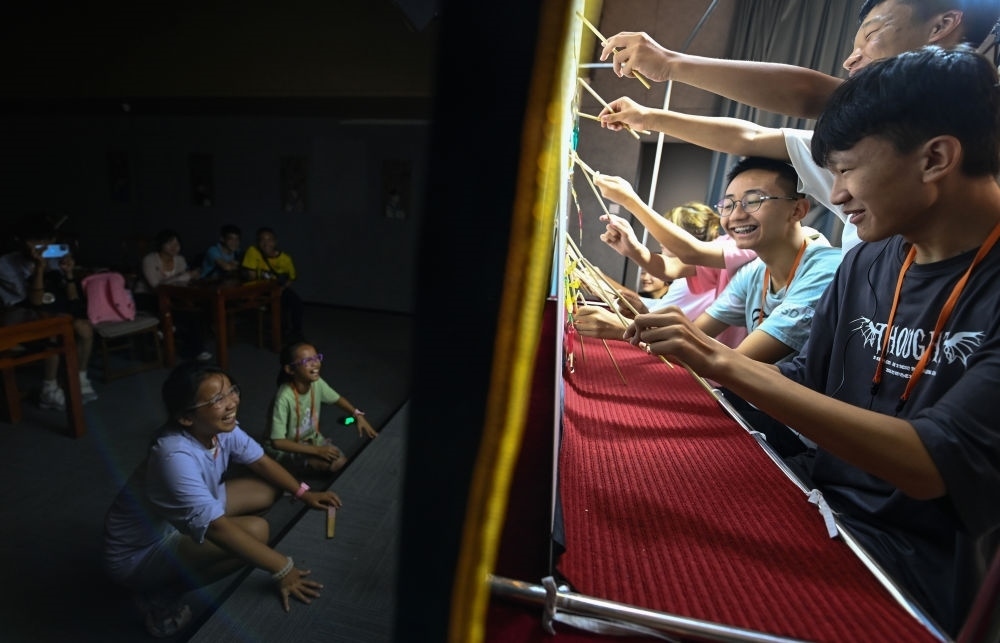 2023年8月8日，進(jìn)行暑期研學(xué)的學(xué)生在位于陜西省西安市的中國秦腔藝術(shù)博物館體驗(yàn)皮影戲演出。新華社記者 鄒競一 攝