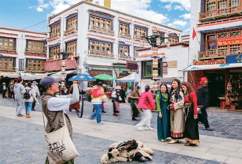 千年八廓街，見證民族團(tuán)結(jié)。2021年7月，習(xí)近平總書記來到位于西藏拉薩老城區(qū)的八廓街，感慨地說：“千年八廓街，是我們各民族建起來的八廓街。各民族文化在這里交流交往交融，我們中華民族的大家庭在這里其樂融融?！眻D為2023年6月13日，游客身著藏裝在八廓街拍照留念。 新華社記者 姜帆/攝