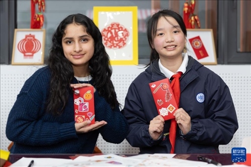 1月28日，美國馬斯卡廷中學(xué)學(xué)生（左）和復(fù)旦大學(xué)第二附屬學(xué)校學(xué)生展示互相送出的寫有寄語祝福的紅包。 新華社記者 王翔 攝