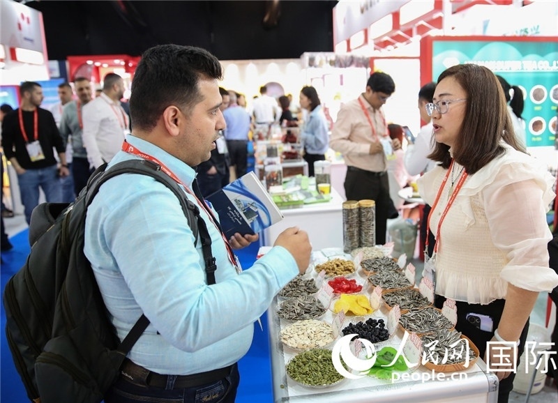 圖為一家中國干果參展企業(yè)代表與采購商洽談。人民網(wǎng) 塔里克·易卜拉欣攝