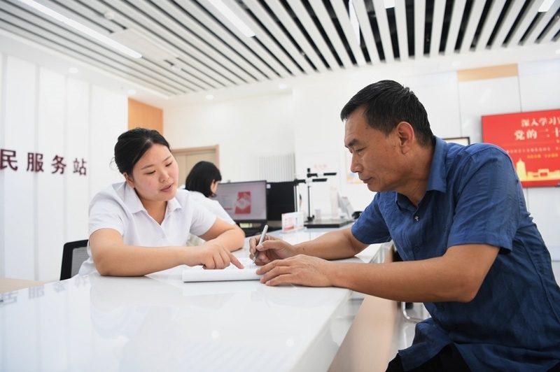 2023年5月23日，河北雄安新區(qū)容東片區(qū)南文營社區(qū)居民（右）在社區(qū)便民服務(wù)站辦理業(yè)務(wù)。