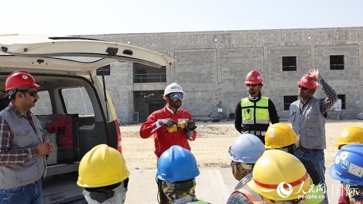 穆薩瓦爾(圖中紅衣人）現(xiàn)場演示工具操作規(guī)范。人民網(wǎng)記者 管克江攝