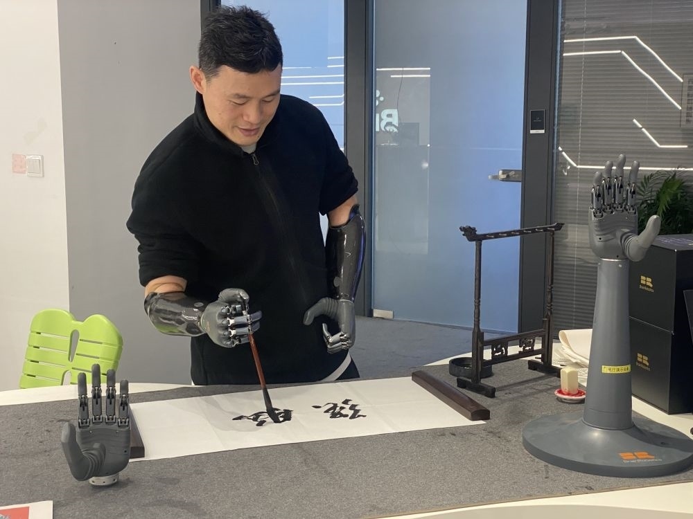 2024年3月29日，在浙江強腦科技有限公司展廳內，失去雙手的產(chǎn)品體驗官倪敏成依靠智能仿生手寫毛筆字。新華社記者 魏一駿 攝