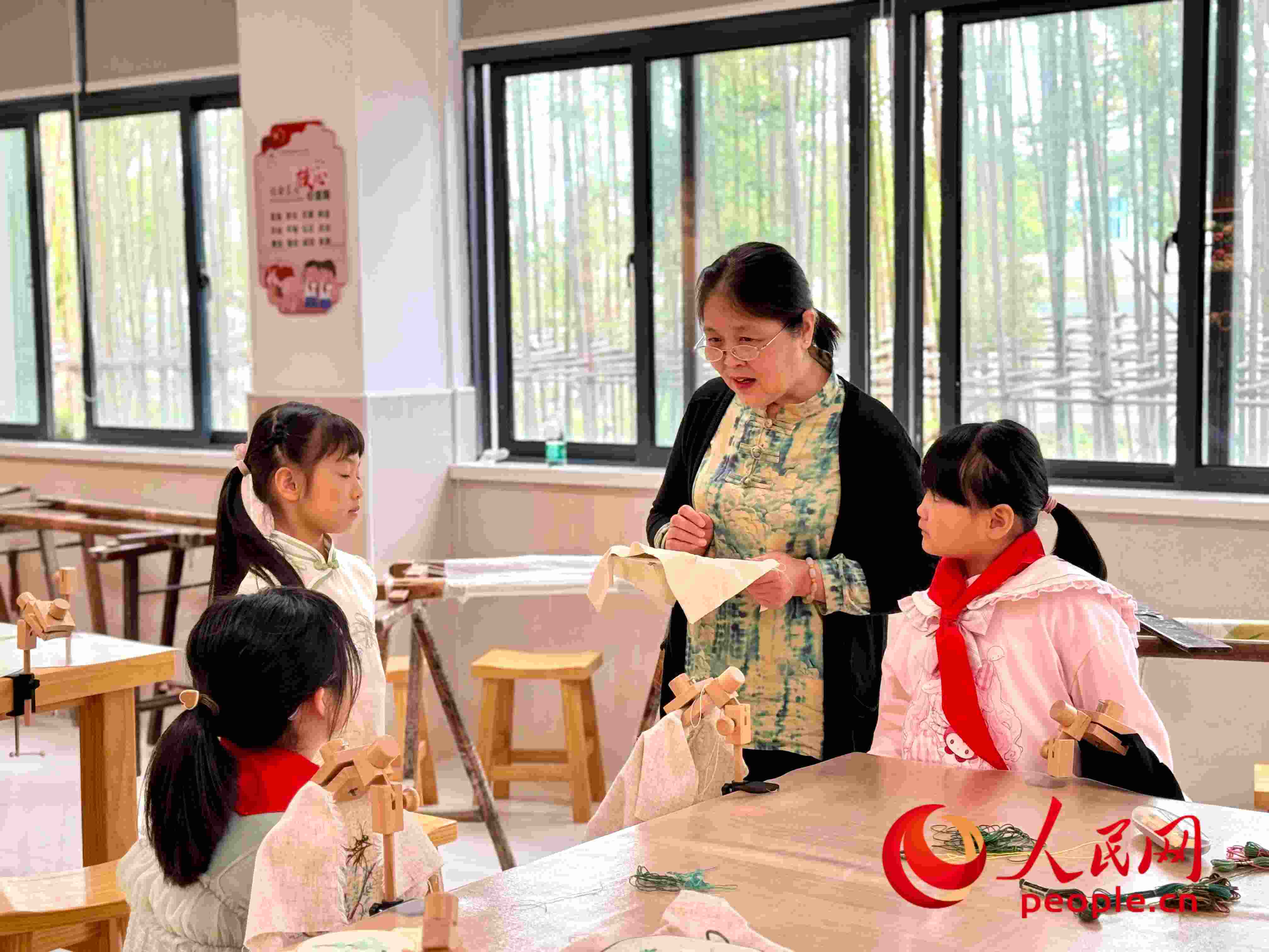 顧建珍（左三）在教孩子們刺繡知識(shí)。人民網(wǎng) 周靜圓攝