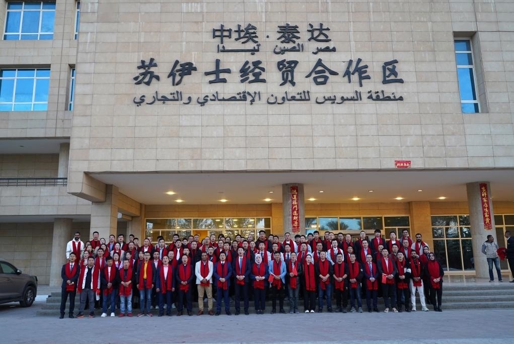 2024年2月11日，在位于埃及蘇伊士省的中埃·泰達(dá)蘇伊士經(jīng)貿(mào)合作區(qū)，中埃員工在合作區(qū)辦公大樓前合影拜年。新華社發(fā)（泰達(dá)合作區(qū)供圖）