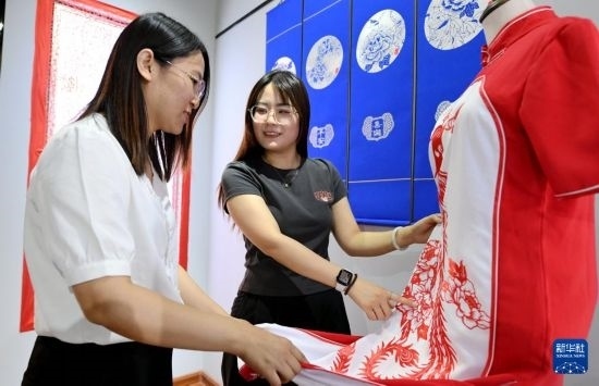 5月31日，在衡水市阜城縣一家剪紙工作室，游客在觀賞帶有剪紙?jiān)氐钠炫邸? width=