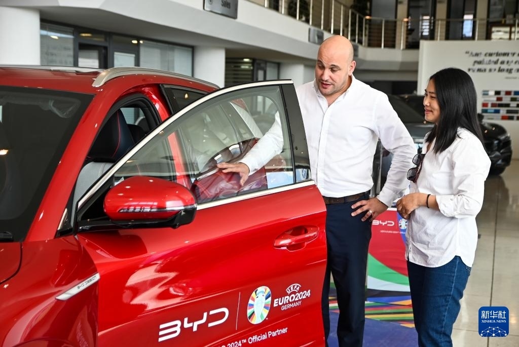 2024年5月29日，在馬耳他比爾基卡拉，馬耳他哈桑-扎米特汽車公司首席執(zhí)行官德古阿拉（左）介紹一輛比亞迪純電動汽車。新華社發(fā)（喬納森·博格 攝）