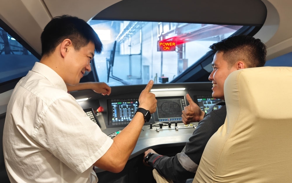 2023年8月25日，在印度尼西亞萬隆的雅萬高鐵德卡魯爾動車所內(nèi)，中國師傅穆振（左）向印尼火車司機塞蒂亞萬講解動車組出庫前的上電作業(yè)。新華社記者 徐欽 攝