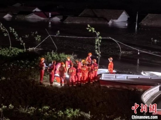  7月6日凌晨3時(shí)，在湖南岳陽(yáng)華容縣團(tuán)洲垸洞庭湖一線堤防，救援人員剛剛完成一次救援任務(wù)，遠(yuǎn)處是被淹的民房。中新社記者 白祖偕 攝