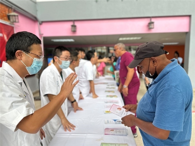 援圭醫(yī)療隊(duì)隊(duì)員們?cè)趩?dòng)儀式上為當(dāng)?shù)孛癖姺职l(fā)宣傳手冊(cè)。中國(guó)援助圭亞那醫(yī)療隊(duì)供圖