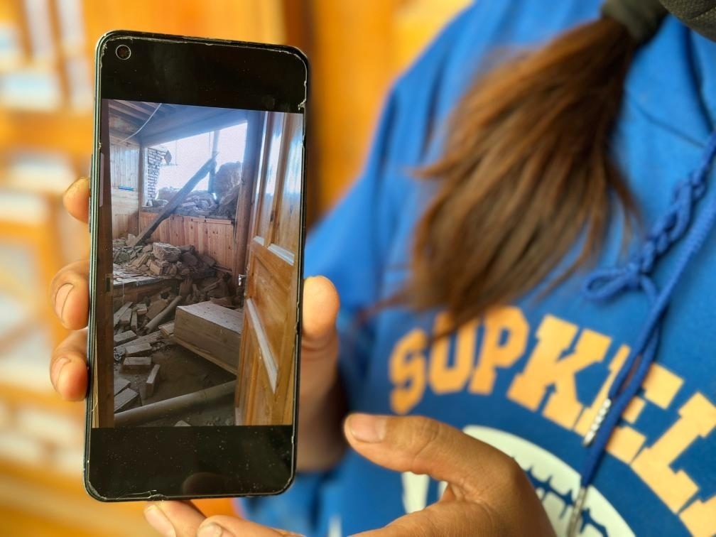 圖為7月17日拉毛東智在手機(jī)上找出地震后房屋受損的照片。新華社記者 張子琪 攝