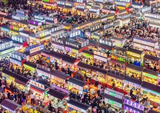 2024年4月21日，人們?cè)诤颖笔≌h小商品夜市品嘗美食（無(wú)人機(jī)照片）。新華社發(fā)（武志偉 攝）