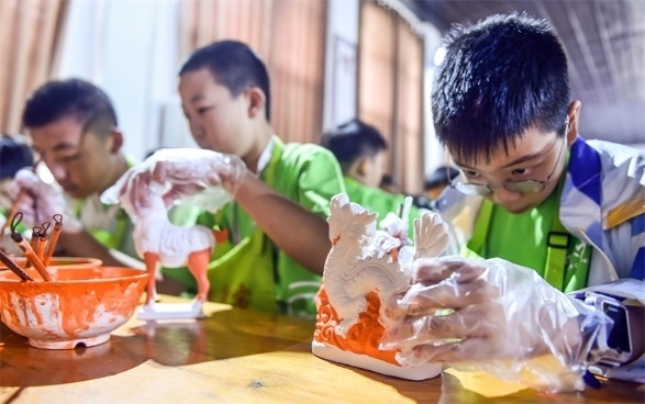 小朋友們?cè)诼尻柺忻辖騾^(qū)朝陽鎮(zhèn)南石山村體驗(yàn)唐三彩素胎施釉技藝。圖片來源：視覺中國