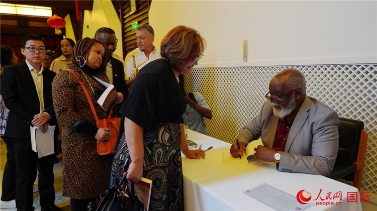 譚哲理在活動(dòng)現(xiàn)場簽名贈(zèng)書。人民網(wǎng) 劉暢攝