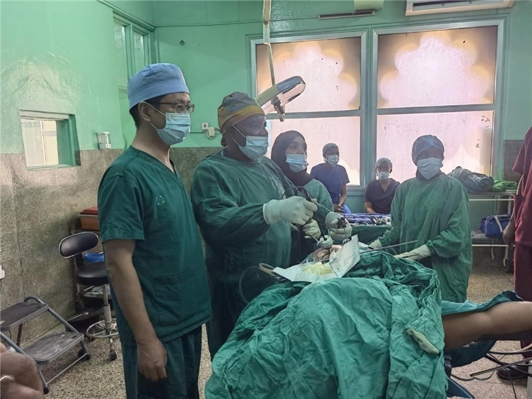 隊長蔣國慶（左一）關(guān)注當(dāng)?shù)蒯t(yī)生手術(shù)情況。中國援桑醫(yī)療隊供圖