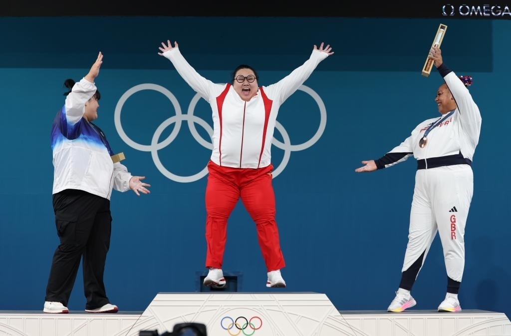 中國(guó)選手李雯雯（中）在巴黎奧運(yùn)會(huì)舉重女子81公斤以上級(jí)頒獎(jiǎng)儀式中登上領(lǐng)獎(jiǎng)臺(tái)（2024年8月11日攝）。新華社記者 楊磊 攝