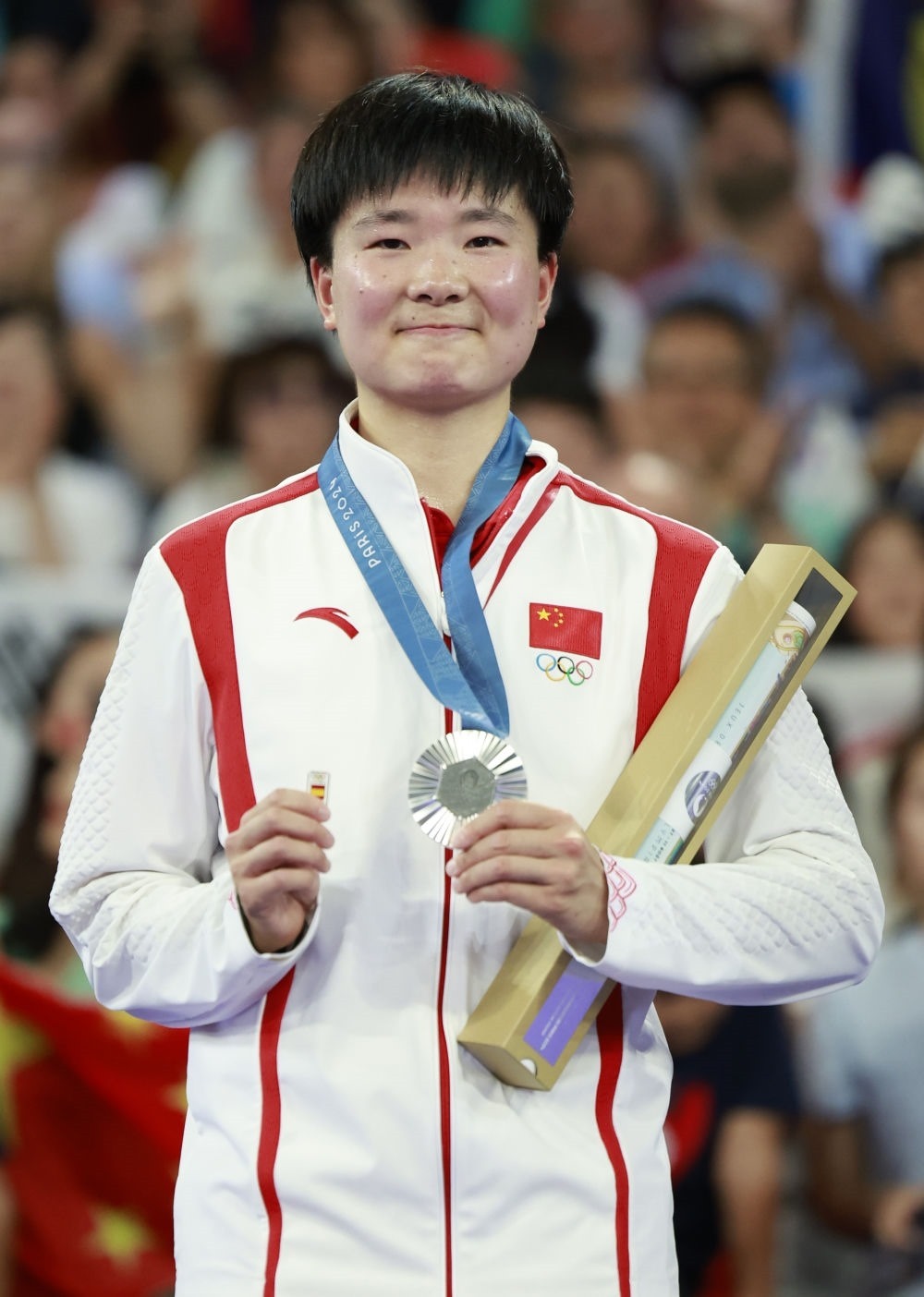 巴黎奧運(yùn)會(huì)羽毛球女子單打亞軍、中國(guó)選手何冰嬌在頒獎(jiǎng)儀式上一手握著銀牌，一手握著西班牙奧委會(huì)徽章（2024年8月5日攝）。新華社記者 任正來(lái) 攝