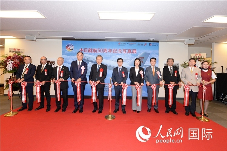 與會(huì)嘉賓共同為中日通航50周年紀(jì)念圖片展開幕剪彩。馮學(xué)敏攝