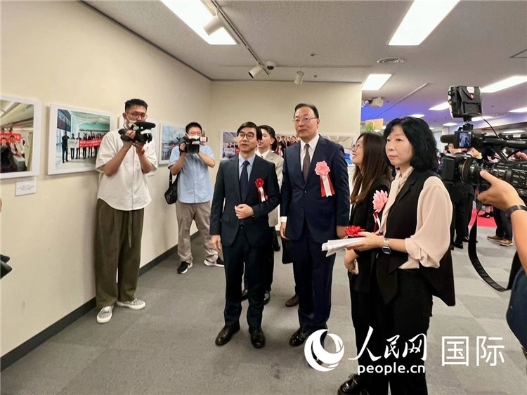 中國國際航空日韓地區(qū)支社支社長馮力為中國駐日本大使館臨時(shí)代辦施泳等嘉賓介紹展出圖片。人民網(wǎng) 許可攝
