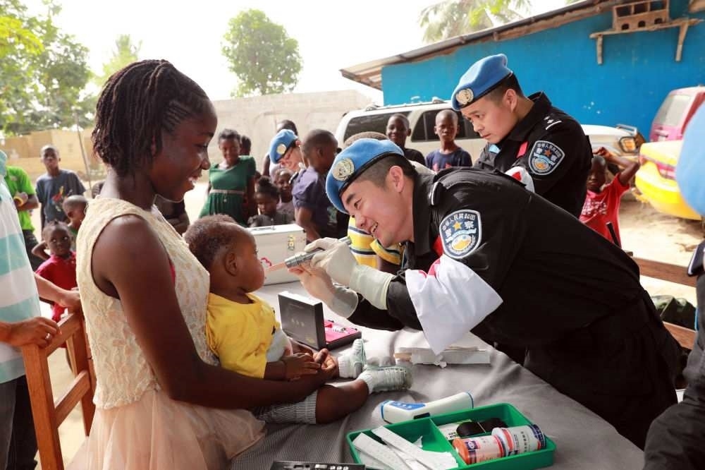 2017年12月28日，在利比里亞蒙羅維亞，中國維和警察防暴隊醫(yī)療人員為兒童做口腔檢查。