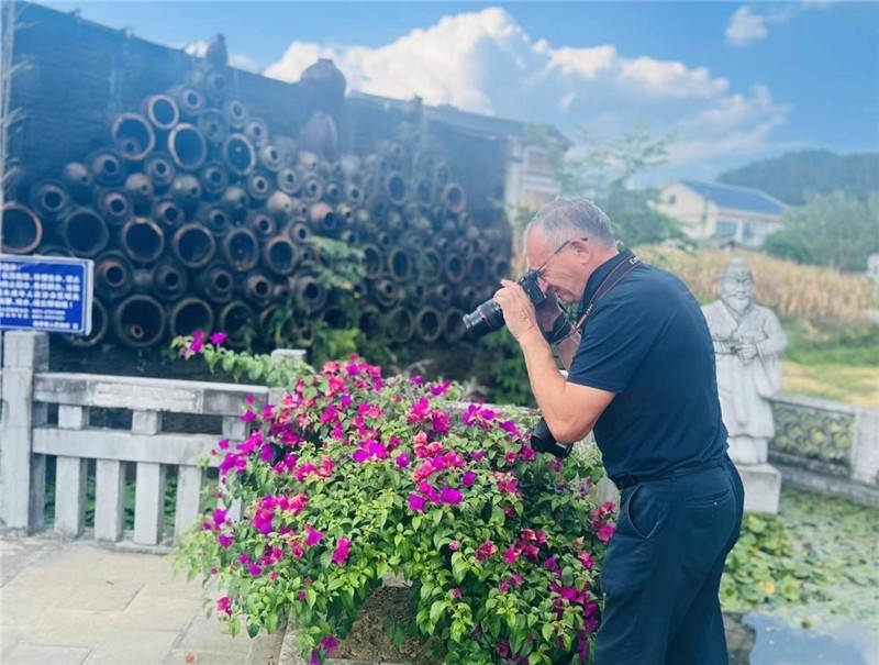 遠(yuǎn)處黔北民居錯落有致，近處一只黑色的蝴蝶穿梭于粉紫色三角梅花叢間隙，與俄羅斯“大歐亞”總編輯弗拉基米爾·別列日內(nèi)赫的鏡頭玩起了捉迷藏，“你追我逃，不亦樂乎”。（張亞欣攝）