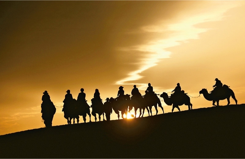 新時代以來，文化和旅游深度融合發(fā)展體制機制不斷健全，成功走出了一條獨具特色的中國旅游發(fā)展之路。圖為2024年9月1日清晨，游客在甘肅省敦煌市鳴沙山月牙泉景區(qū)乘騎駱駝，欣賞大漠風(fēng)光，體驗絲路風(fēng)情。 新華社發(fā) 張曉亮/攝