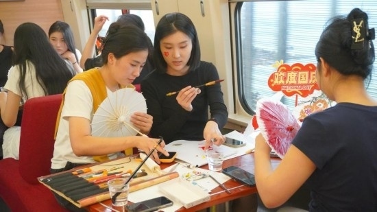 10月1日，旅客們?cè)贕1634次列車上給油紙傘作畫(huà)。新華社記者周義 攝