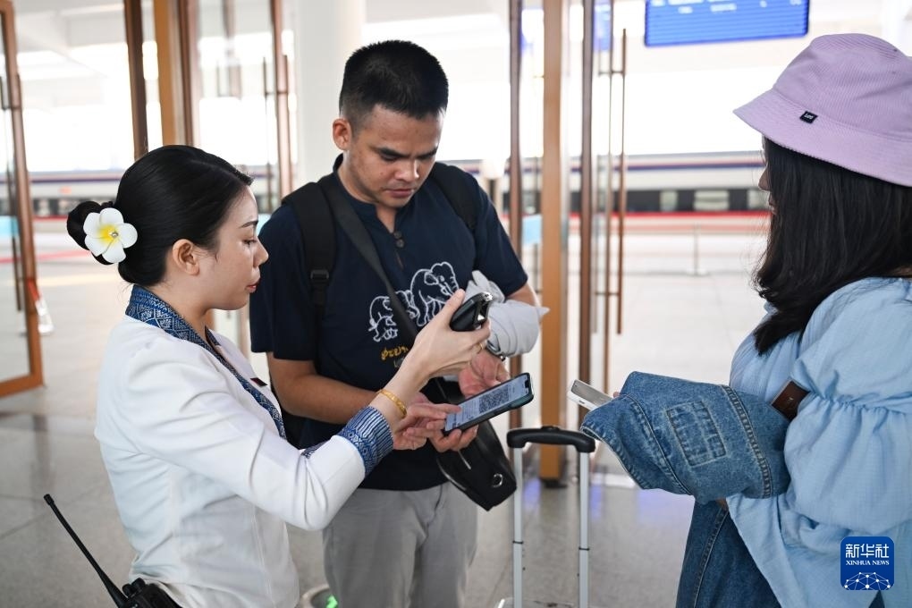 10月12日，在老撾萬象中老鐵路萬象站，工作人員檢驗(yàn)乘客車票。新華社記者 程一恒 攝