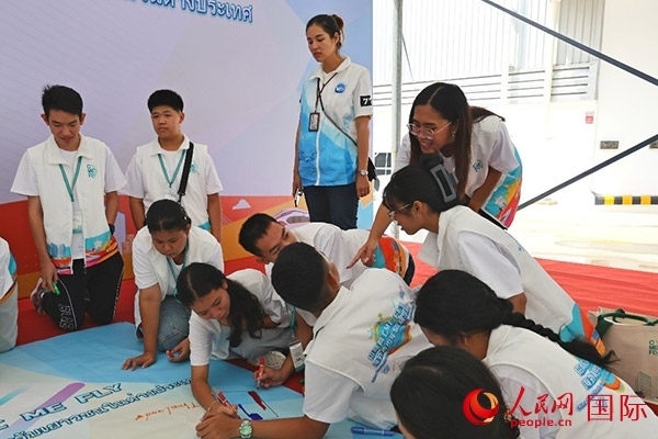泰國學(xué)生在開營儀式展板上繪制圖案。人民網(wǎng)記者 白元琪攝