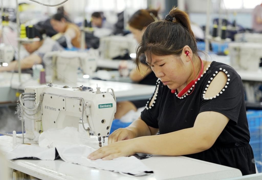 5月20日，村民在李寨村服裝加工廠內(nèi)忙碌。河南省周口市沈丘縣馮營(yíng)鎮(zhèn)李寨村地處豫東平原。近年來，乘著脫貧攻堅(jiān)與鄉(xiāng)村振興政策的東風(fēng)，李寨村積極探索產(chǎn)業(yè)發(fā)展模式，通過“龍頭企業(yè)+村集體經(jīng)濟(jì)+農(nóng)戶”的方式，逐漸發(fā)展形成肉牛養(yǎng)殖、設(shè)施農(nóng)業(yè)、服裝加工、康養(yǎng)民宿等產(chǎn)業(yè)，以產(chǎn)業(yè)振興助力鄉(xiāng)村振興。新華社記者 李嘉南 攝