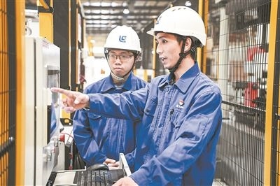 在廣西柳工機(jī)械股份有限公司生產(chǎn)車間內(nèi)，一名高級技師（右）給徒弟講解數(shù)控設(shè)備操作細(xì)節(jié)。新華社記者 曹祎銘攝