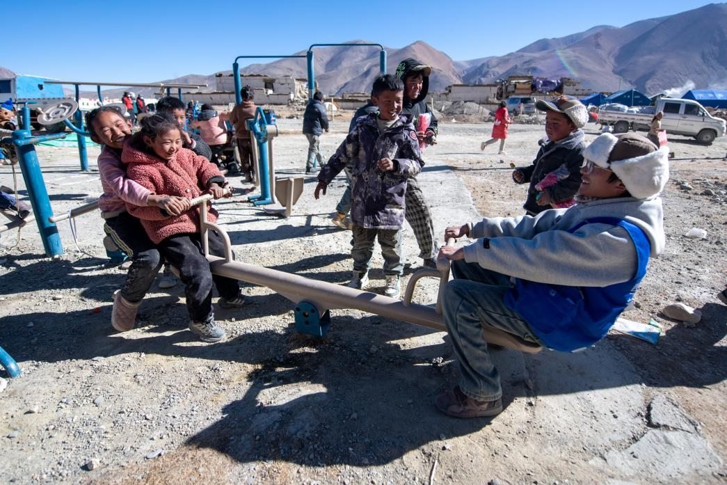 1月11日，在定日縣措果鄉(xiāng)塘仁村安置點，西藏星光社會工作服務中心志愿者和孩子們一起玩耍，進行災后心理疏導。人民網(wǎng)記者 翁奇羽攝
