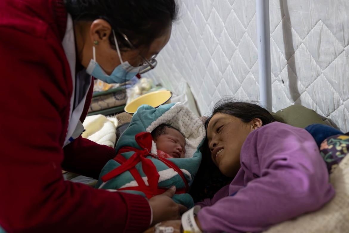 1月10日，定日縣中心醫(yī)院的婦產科醫(yī)生悉心照看一位母親和她懷里的新生兒。人民日報記者張武軍攝