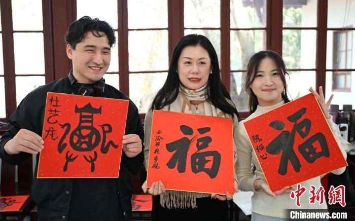 1月20日，外籍留學(xué)生和西泠印社社員李硯(中)展示各自創(chuàng)作的福貼。當(dāng)日，來自巴西、馬來西亞、加納、哈薩克斯坦的外籍留學(xué)生在浙江杭州西泠印社體驗(yàn)福貼、春聯(lián)和篆刻，感受古老的中國傳統(tǒng)文化。中新社記者 王剛 攝